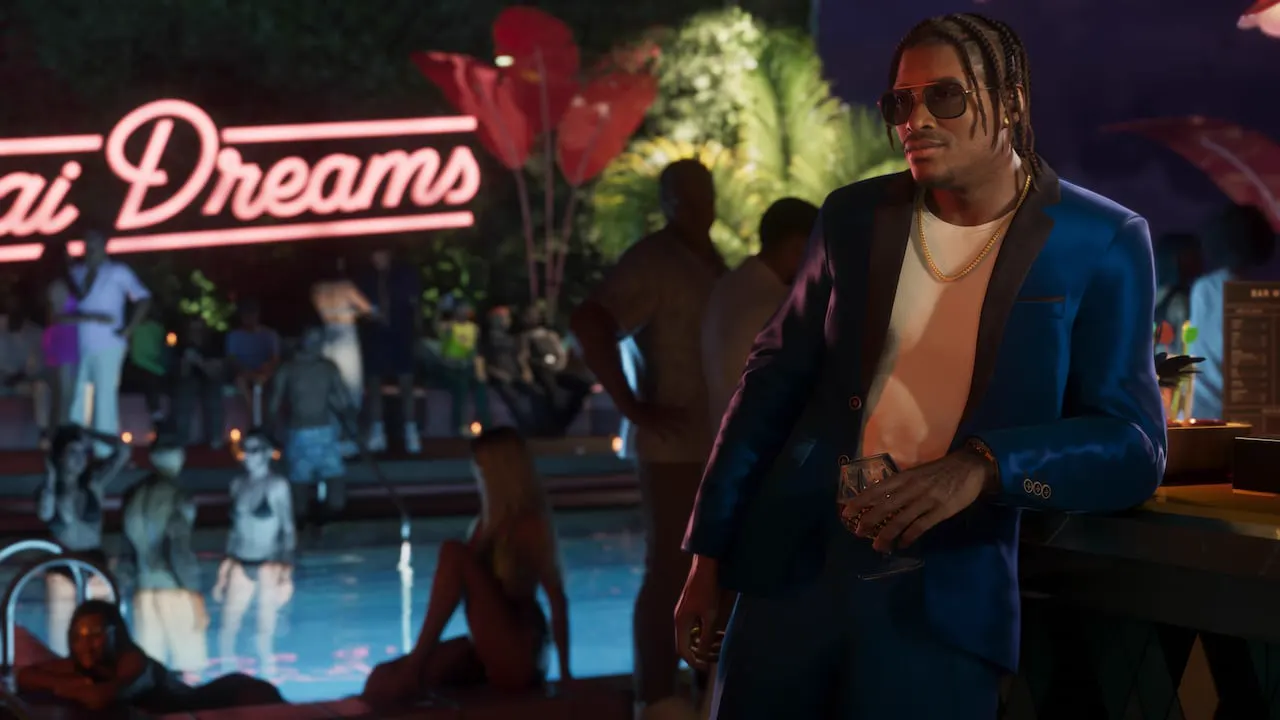 Dre'Quan de traje apoyado en la barra en una fiesta nocturna en la piscina. Los invitados, al fondo, llevan trajes de baño.
